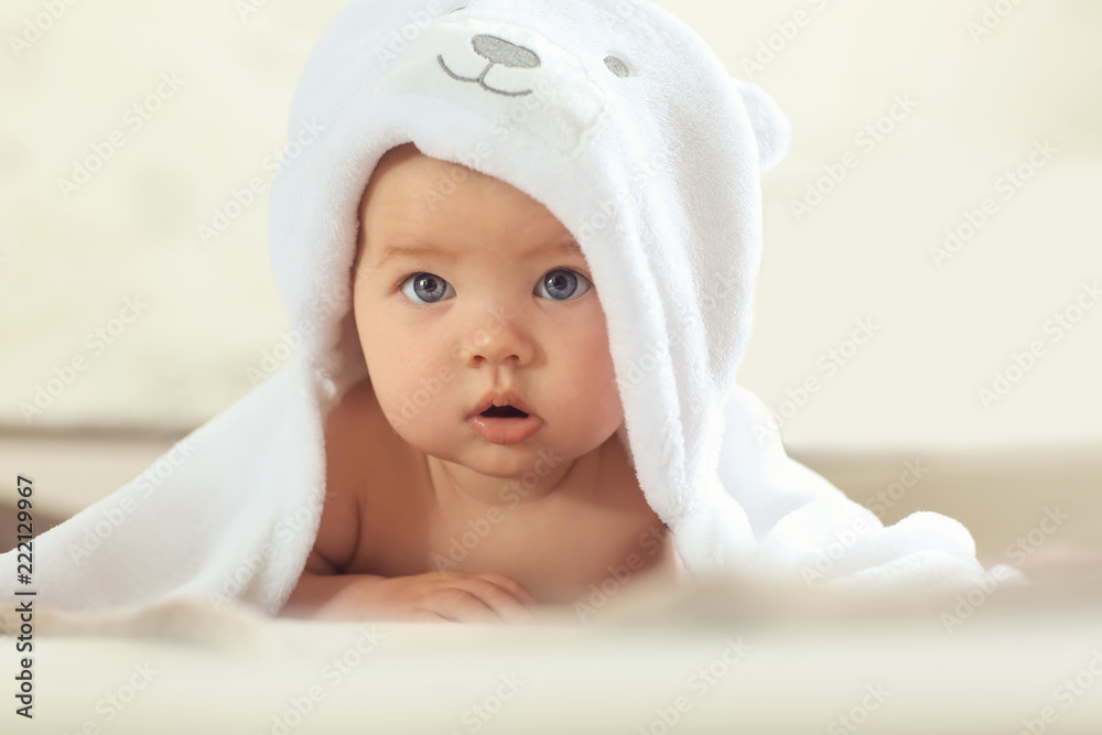 Cute baby with towel lying on bed at home