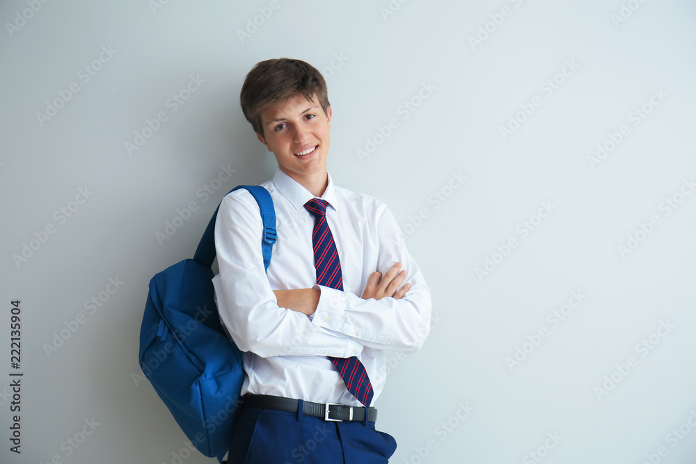 Teenage boy with backpack on light background