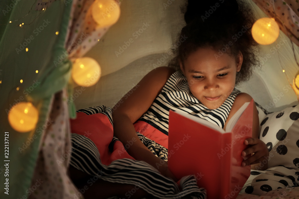 Little African-American girl reading bedtime story in hovel