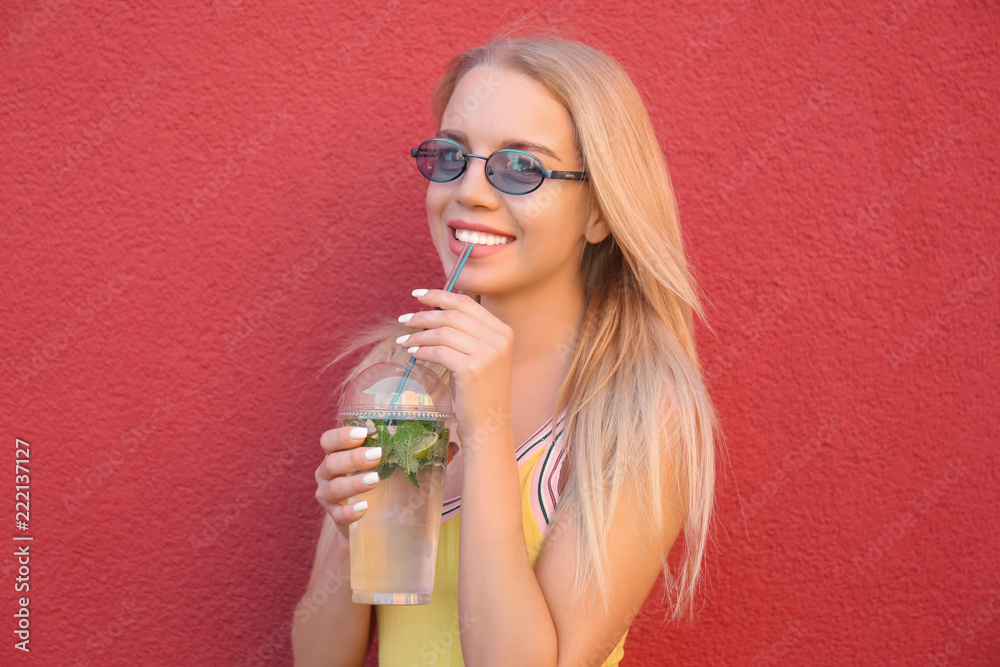 Beautiful young woman with plastic cup of fresh cocktail on color background