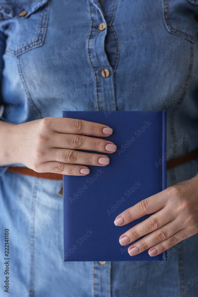 Woman with professional manicure holding notebook, closeup