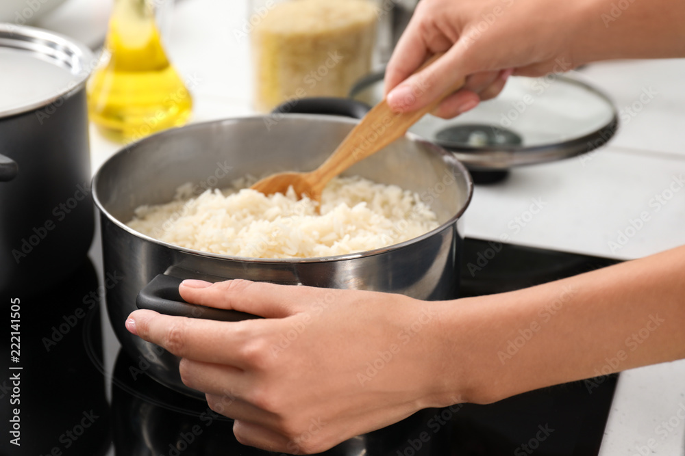 Woman cooking rice on stove in kitchen, closeup