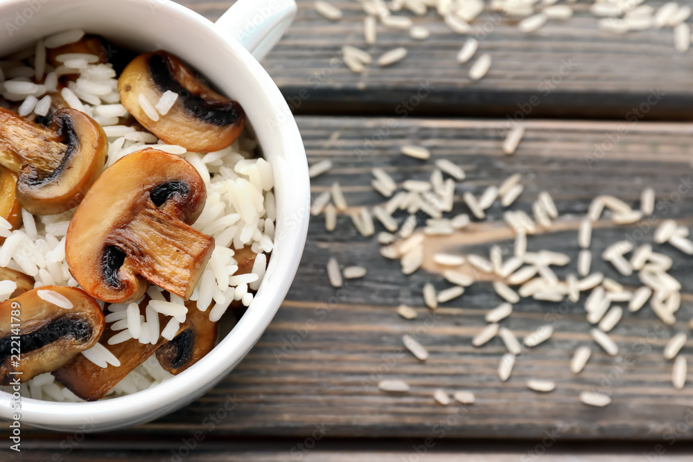 Casserole with tasty boiled rice and mushrooms on wooden table