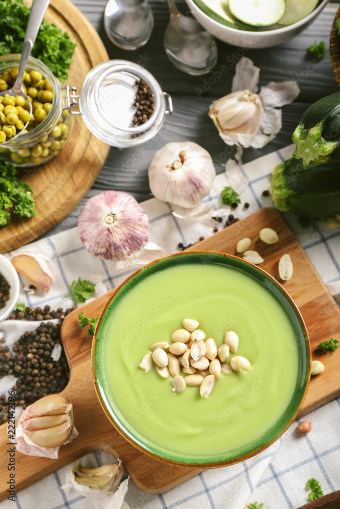 Bowl with tasty zucchini soup on wooden board