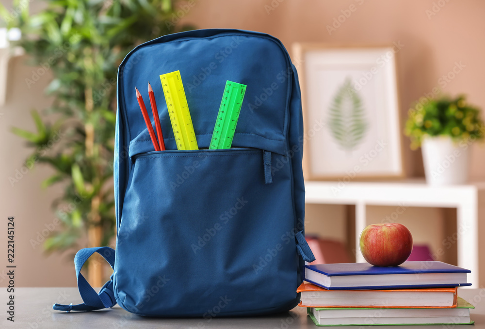 Backpack with school supplies on table indoors