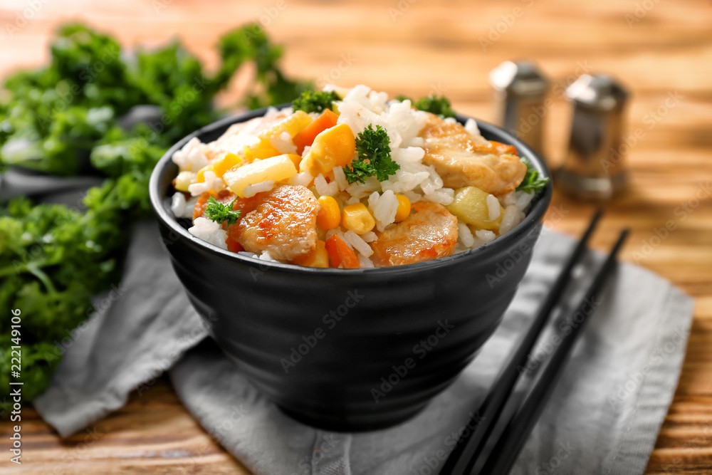 Bowl with boiled rice, meat and vegetables on wooden table