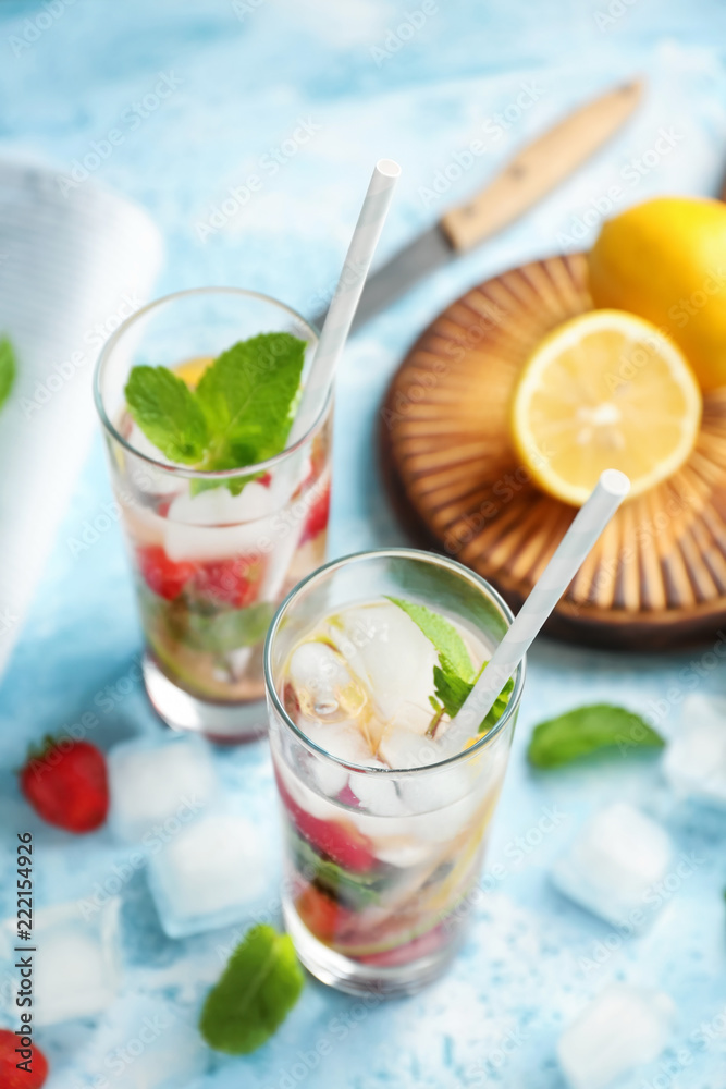 Glasses of fresh strawberry lemonade on color table