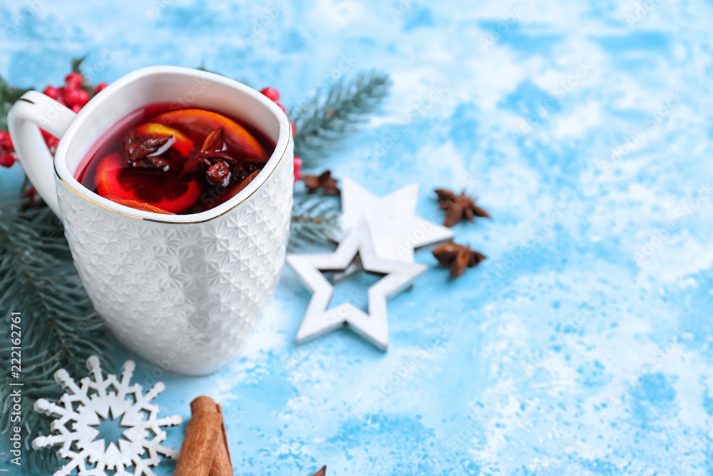 Cup of delicious mulled wine on color table