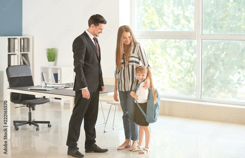 Young woman and her daughter meeting with headmaster at school