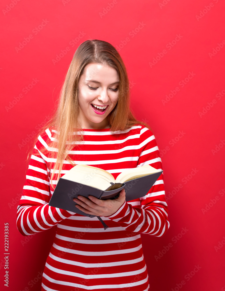 Young woman with a book on a red background