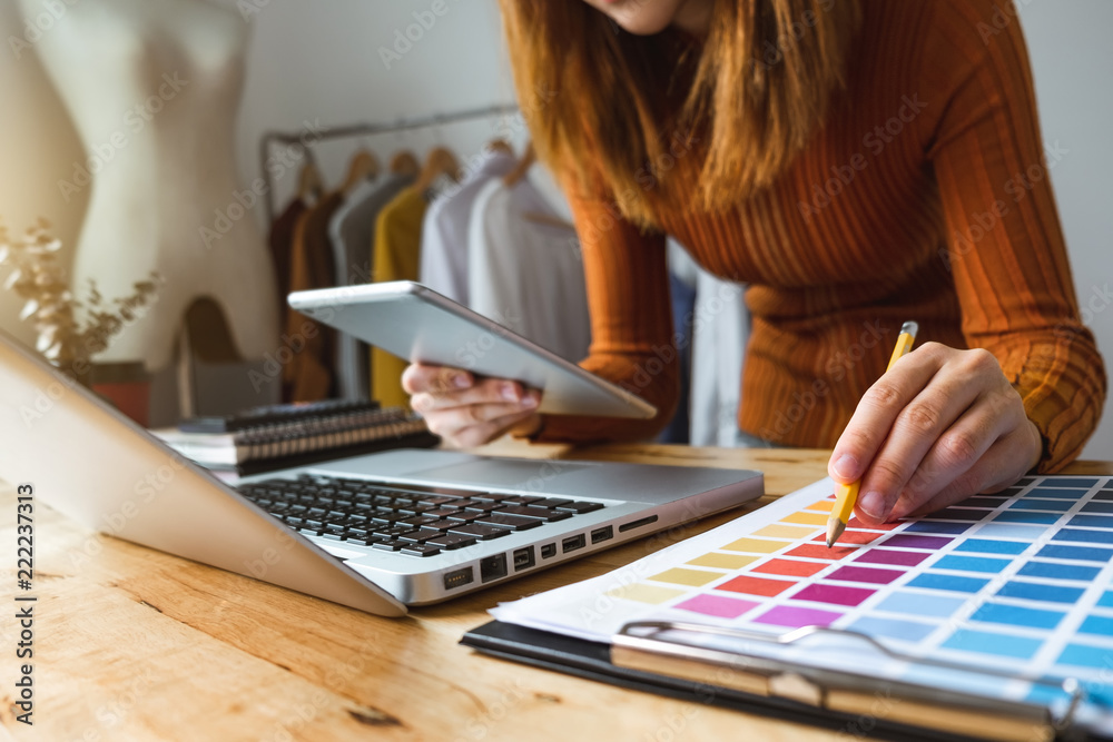 Fashion designer woman talking smart phone and using laptop with digital tablet computer in modern s