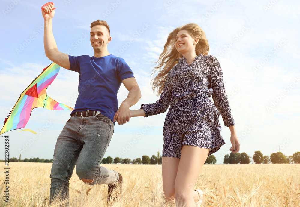 Happy young couple flying kite in a field