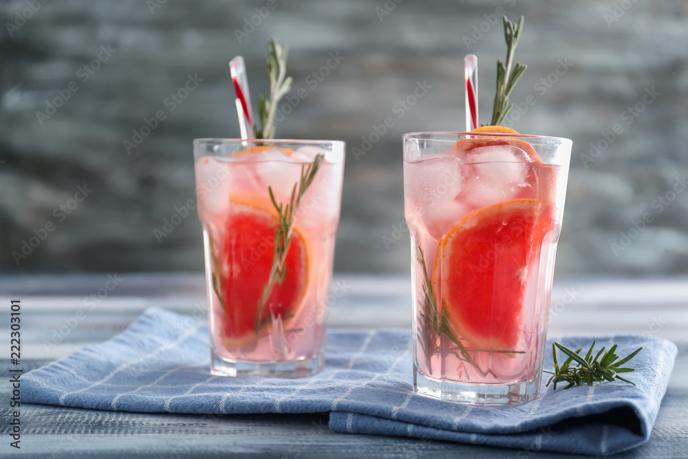 Fresh grapefruit cocktail with rosemary in glasses on wooden table