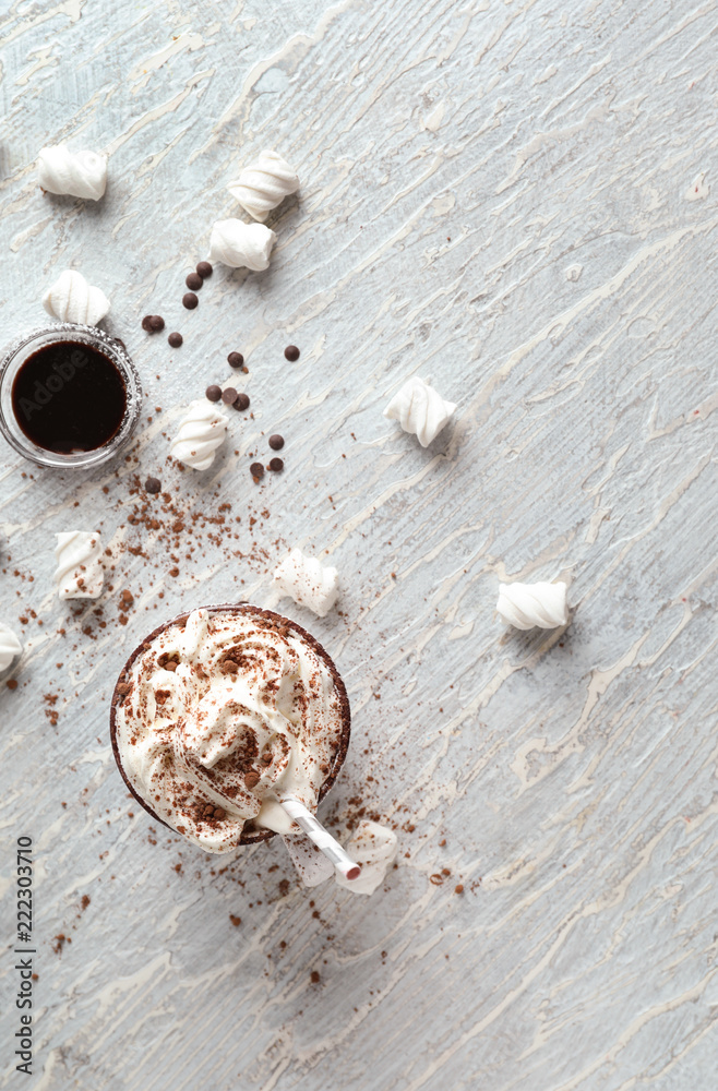 Cup of delicious cocoa with cream and marshmallows on light table