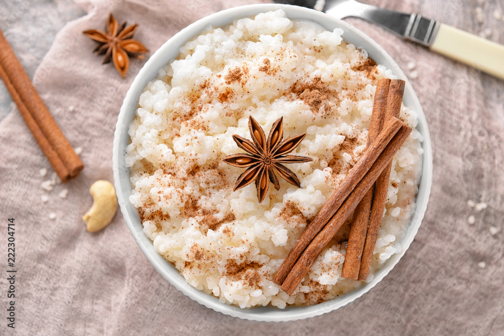 Bowl with tasty rice pudding, cinnamon and anise on gauze cloth