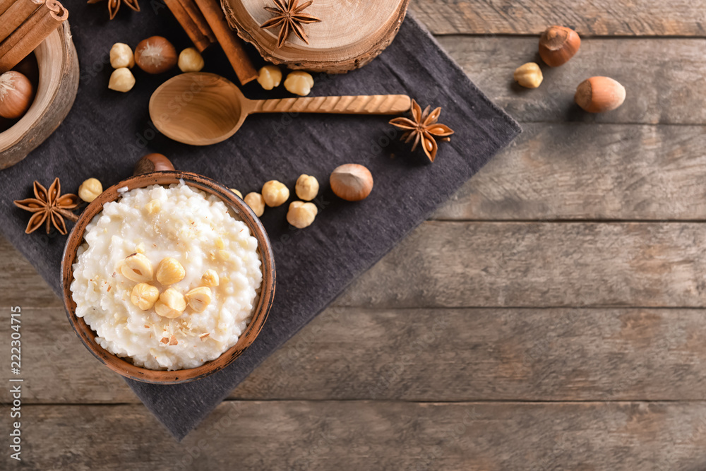 Bowl with delicious rice pudding and hazelnuts on wooden table