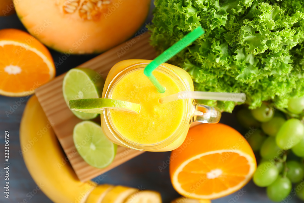 Mason jar of tasty yellow smoothie and ingredients on wooden table