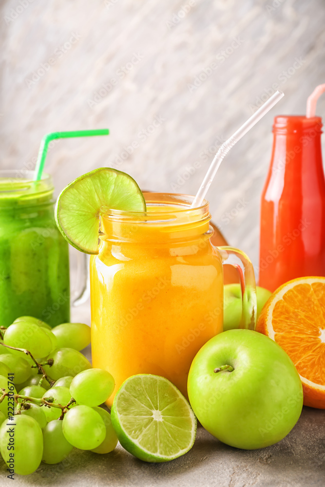 Glassware of tasty smoothies with fruits on grey table