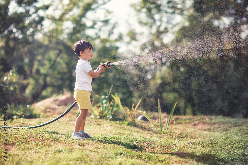 small boy watering lawn with sprinkler