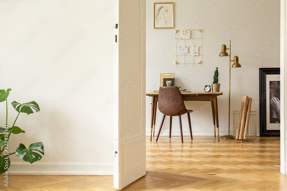 View through an open door into an artists workspace interior with a vintage, leather chair, kraft p