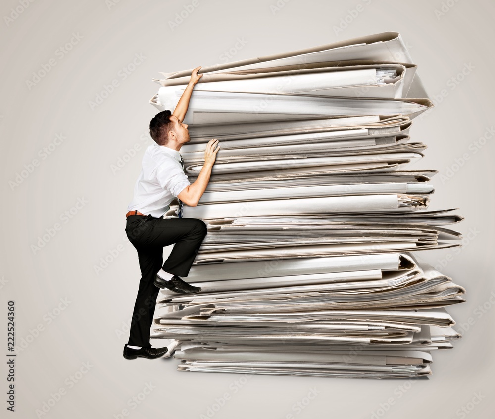 Businessmen climbing up a pile of documents