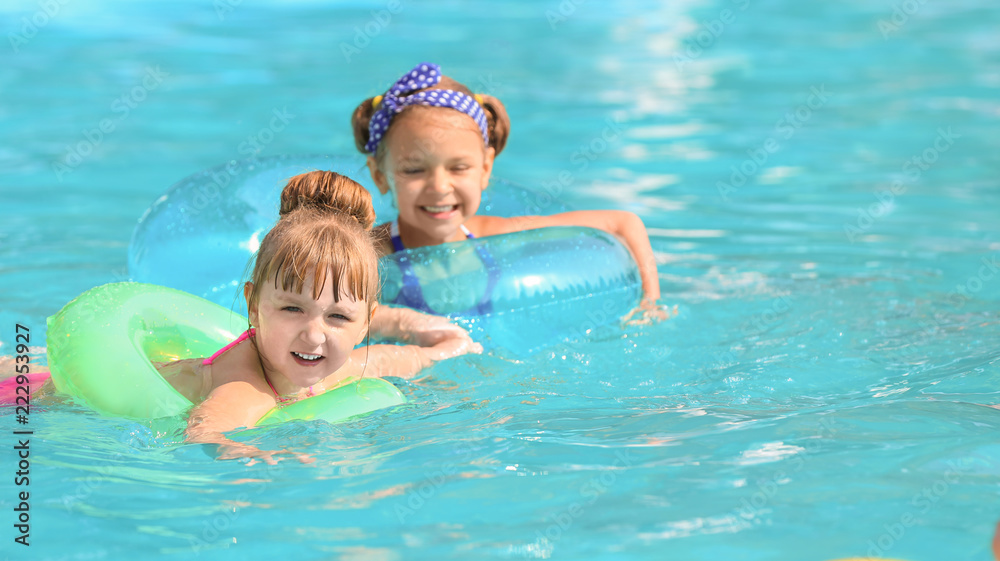 Cute children swimming in pool on summer day