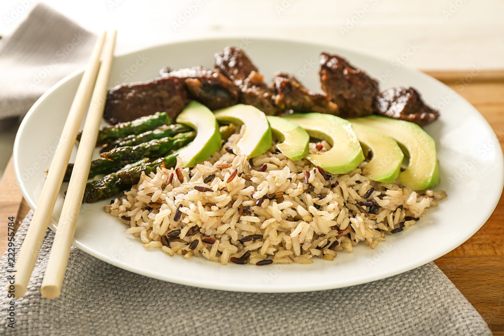 Plate with boiled rice, vegetables and meat on board, closeup