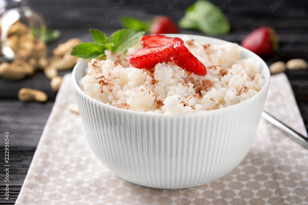 Bowl with delicious rice pudding and strawberry on napkin