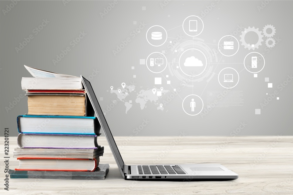 Stack of books with laptop on wooden