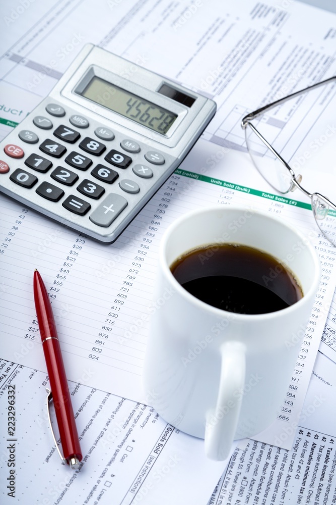 Calculator, Pen, Eyeglasses and Coffee on Financial Figures