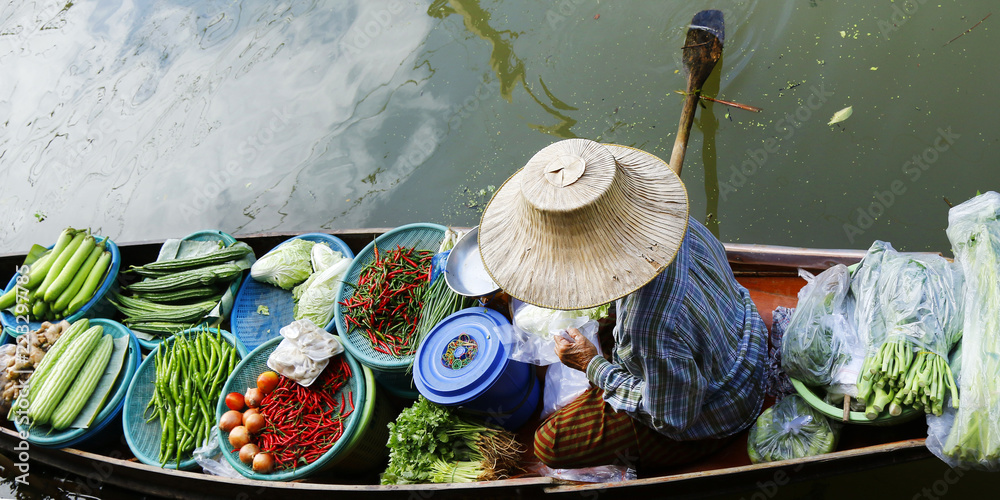 泰国Damnoen Saduak浮动市场，一名妇女在船上交易水果和食物