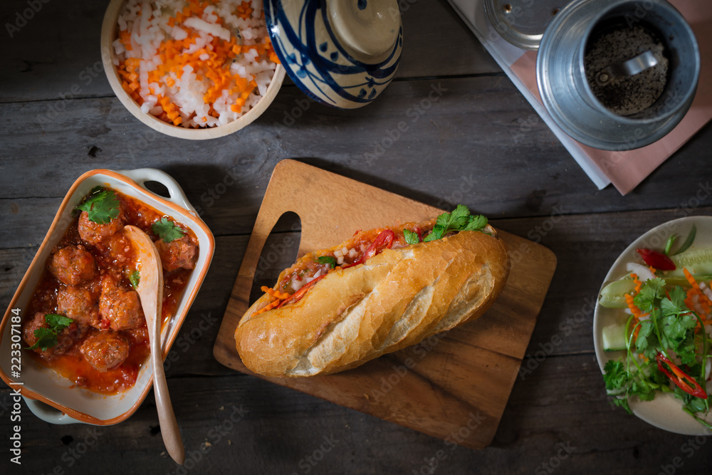 Vietnamese sandwich bread with meatballs in tomato sauce and radish, carrot pickle, cucumber, corian