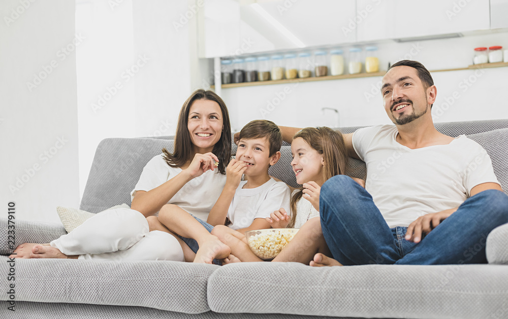 Young family watching TV together at home and having fun together