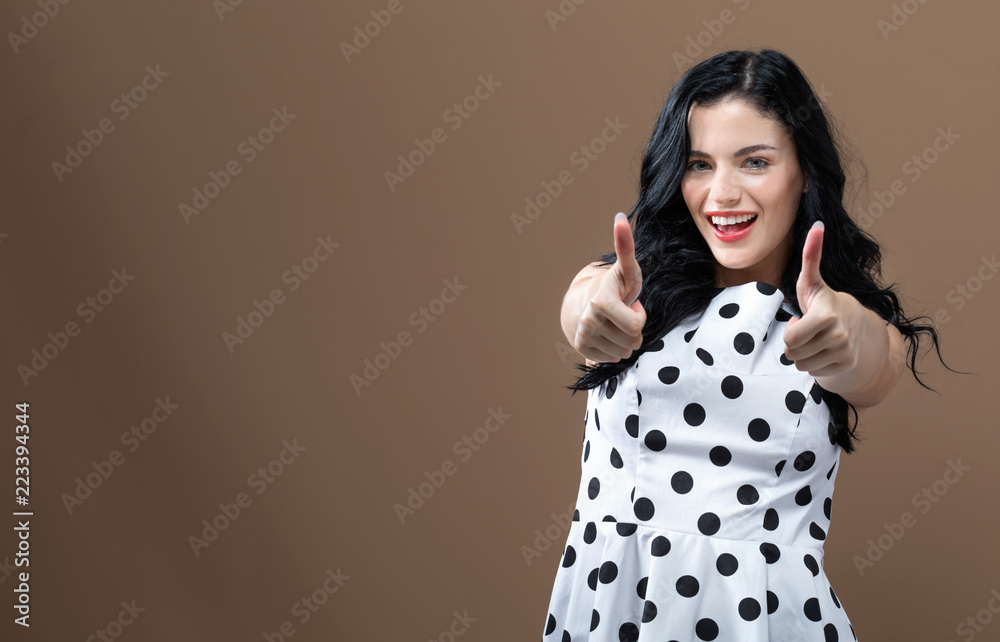 Young woman giving thumbs up on a solid background