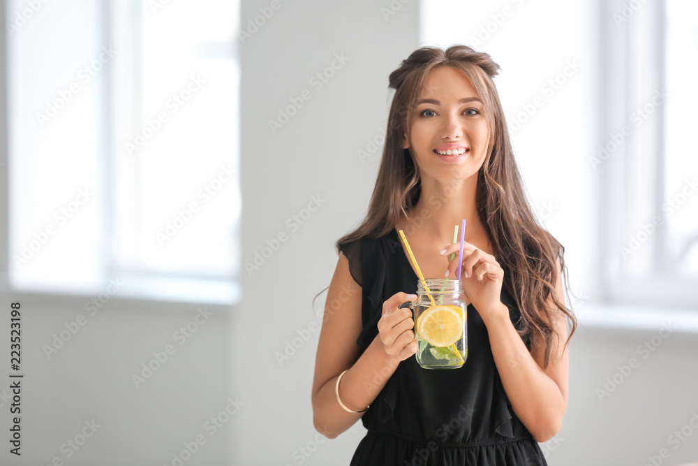 家里拿着梅森瓶新鲜柠檬水的年轻女人