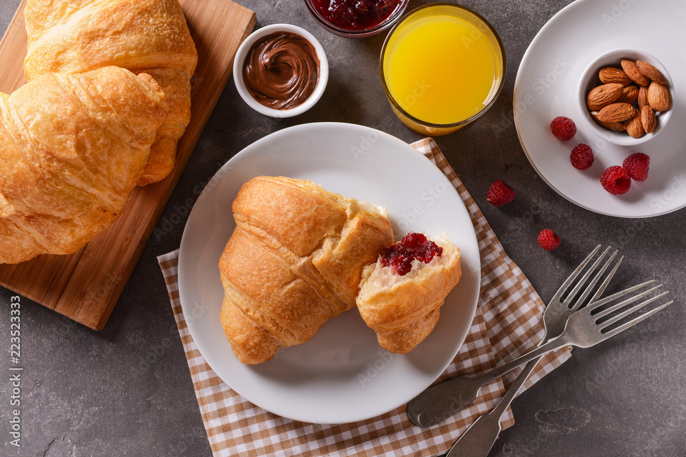 Tasty croissants with glass of orange juice on grey table