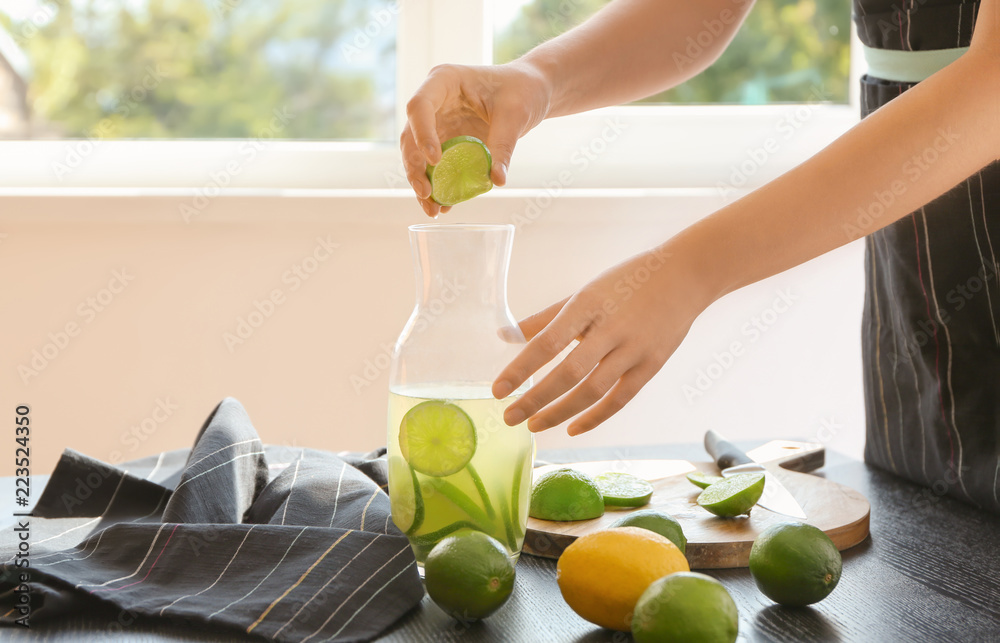 Woman preparing lime lemonade at table