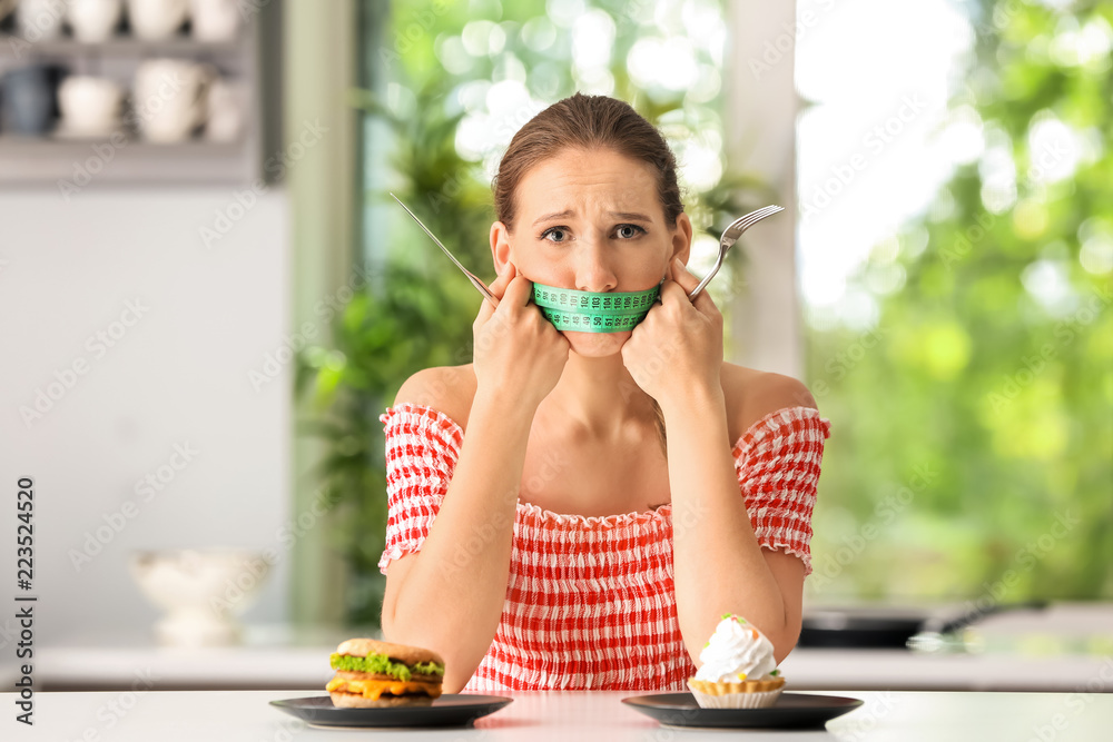 嘴上缠着卷尺、厨房里有不健康食物的情绪化女性。饮食概念