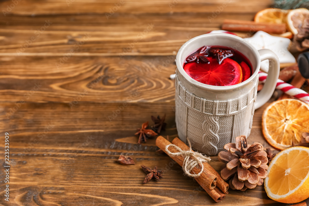 Cup of delicious mulled wine on wooden table