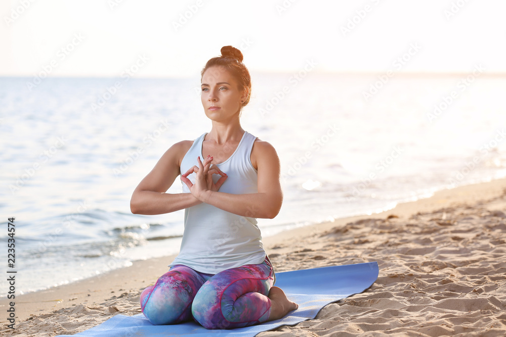 Woman practicing yoga on sea shore