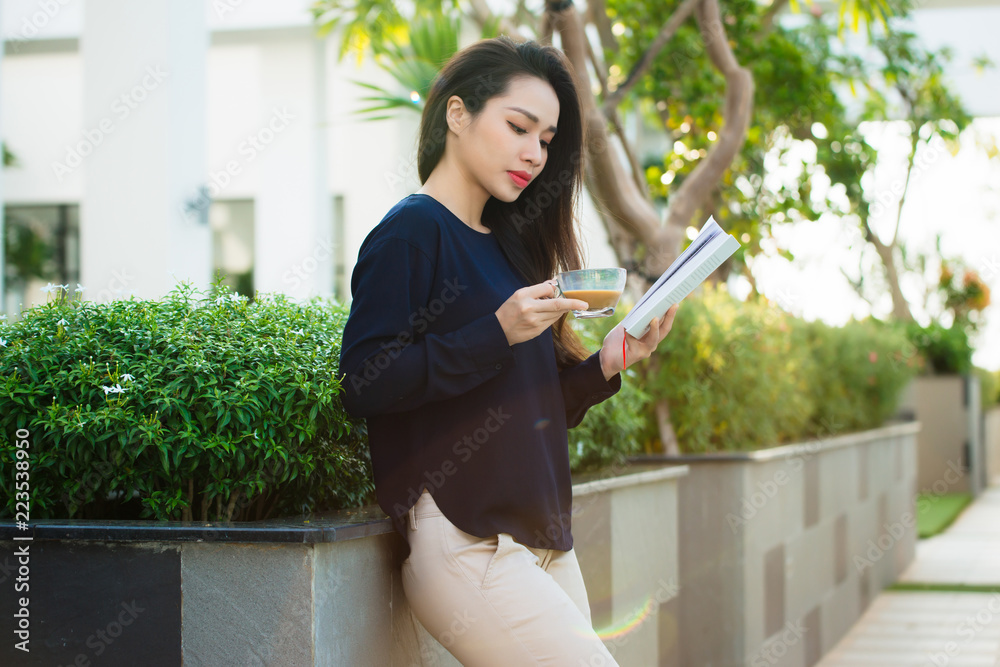 快乐的年轻女人拿着喜欢文学的书在露台上分析小说