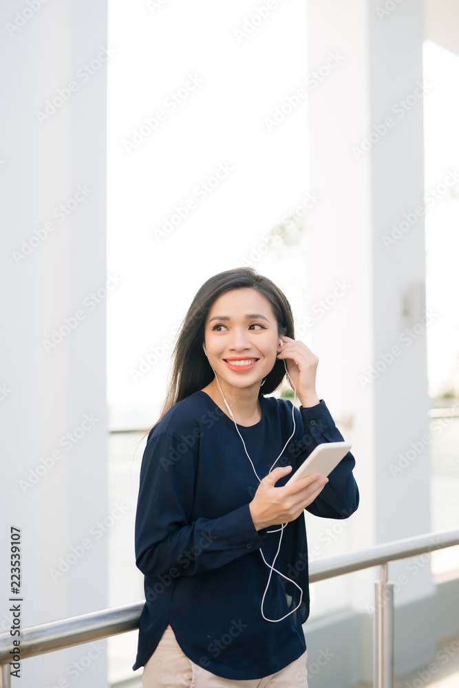 This is my favorite song. Attractive young brunette girl listening to music on the phone while sitti