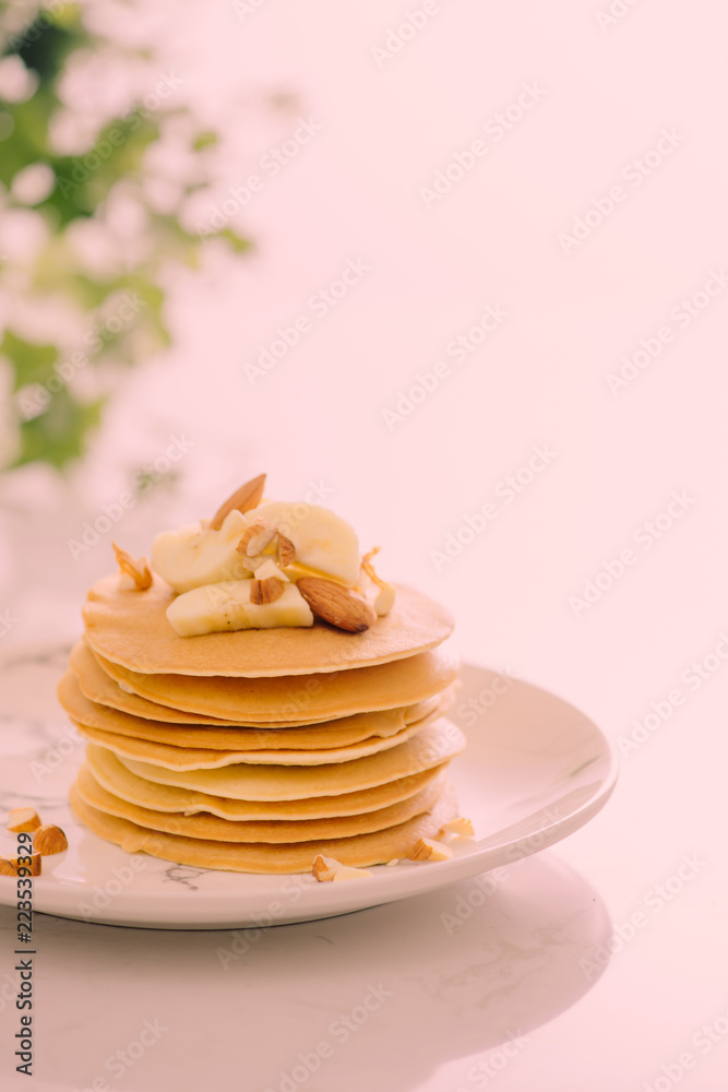 一堆美味的煎饼，里面有巧克力、蜂蜜、坚果和香蕉片，放在石头背上的盘子里