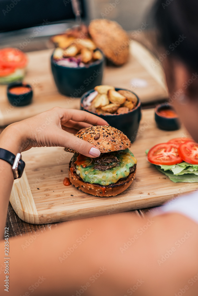 吃素食汉堡的年轻女人。后视图。