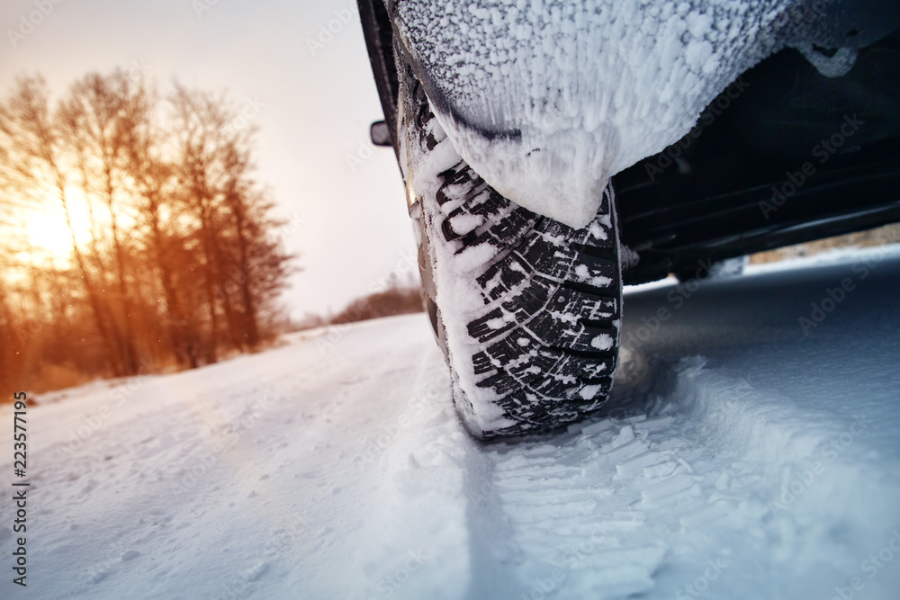 冬季道路上的汽车轮胎被雪覆盖。早晨下雪时，车辆在雪地上行驶