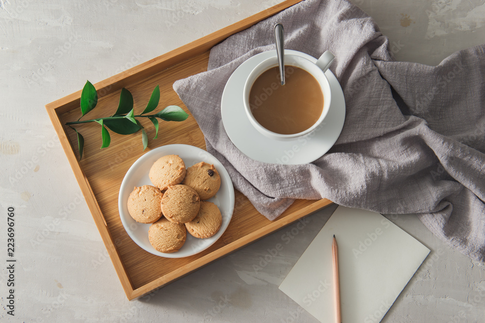 用纸和铅笔在白色杯子盘子里放饼干的茶