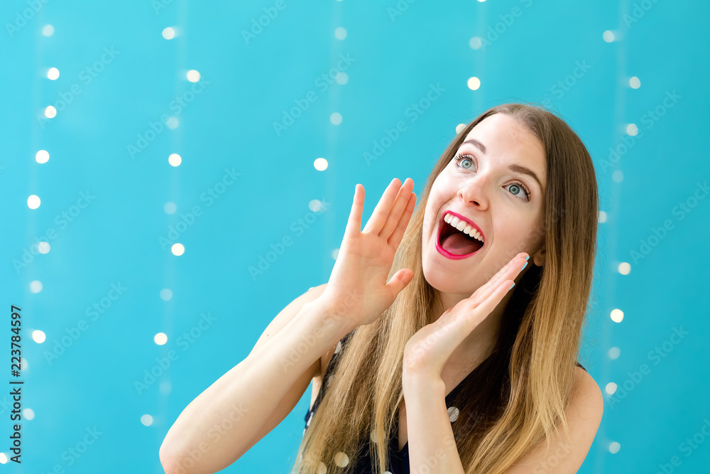 Young woman shouting on a shiny light background