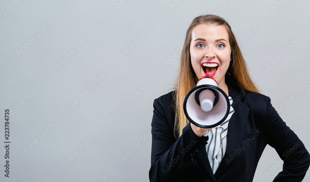 Young woman with a megaphone on a gray background