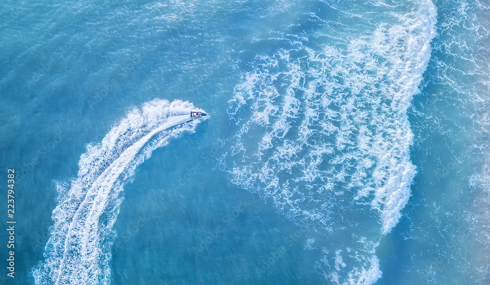 Scooter at the sea surface. Aerial view of luxury floating boat on transparent turquoise water at su