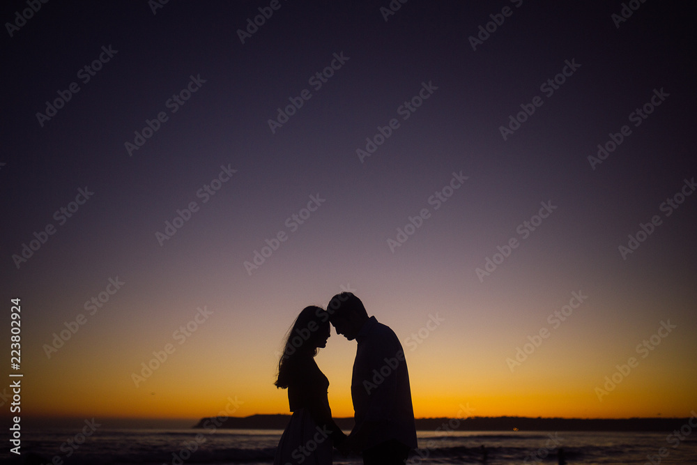 Couple near the ocean at sunset men and woman silhouette